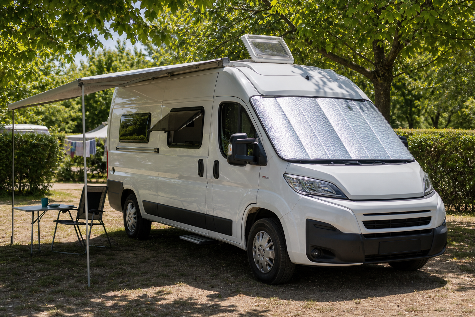 Witte camper in schaduw met buitenzonwering, lage luchttoevoer en geopende dakventilatie