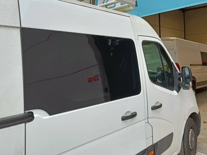 Vast verlijmd donker automotive zijraam in een witte bestelwagen