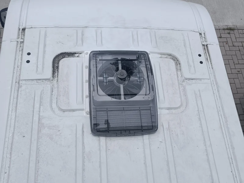 Bovenaanzicht van een MaxxFan Deluxe met geopende kap op een wit camperdak