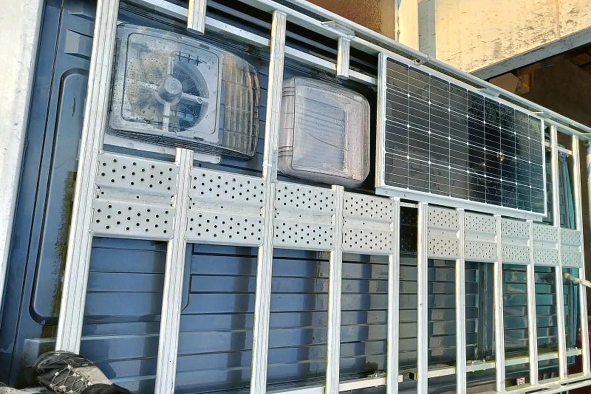 Dakplan met zonnepaneel, dakluiken en ventilatie op een buscamper